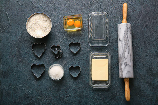 Σύνθεση με υλικά και σκεύη για την προετοιμασία γευστικών μπισκότων σε σκούρο φόντο. Γιορτή του Αγίου Βαλεντίνου - Φωτογραφία, εικόνα