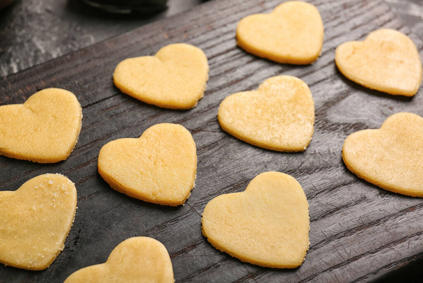 Wooden board with raw heart shaped cookies, closeup. Valentines Day celebration - Foto, Bild