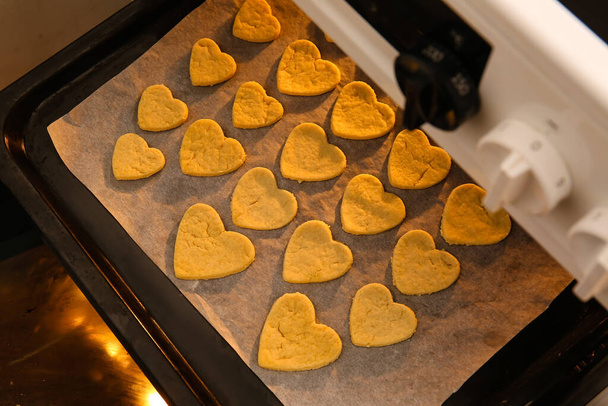 Baking tray with sweet heart shaped cookies in oven, closeup. Valentines Day celebration - Photo, Image