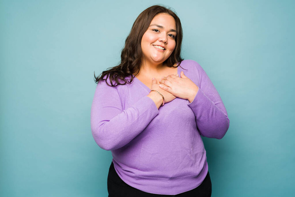 Beautiful loving obese woman touching her chest to her heart and feeling in love smiling - Foto, immagini
