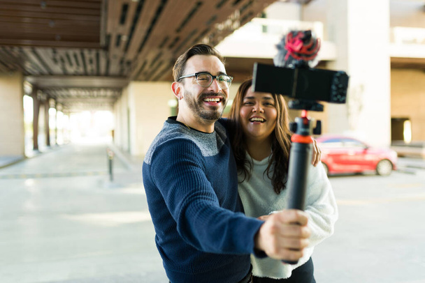 Cheerful couple and influencers filming a video blog together while having fun making content for social media - Foto, Bild