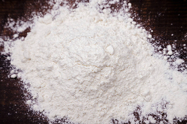 Mountain of fresh flour on a wooden table, basic ingredient for  - Foto, Imagem