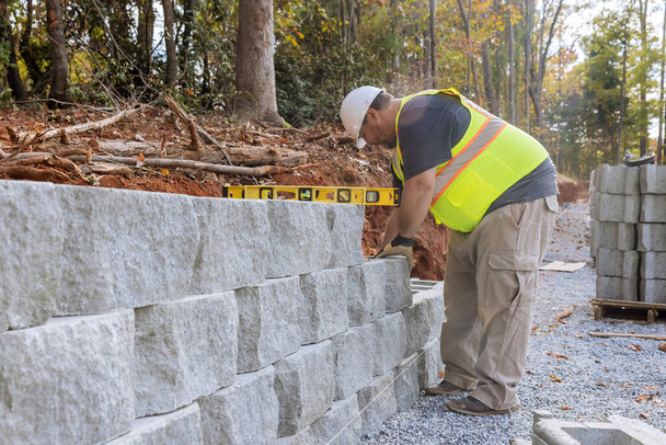 Construction worker building retaining block wall being built on new property - Photo, Image