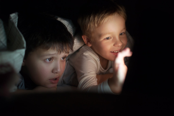 Két fiú néz film vagy rajzfilm pad éjjel - Fotó, kép