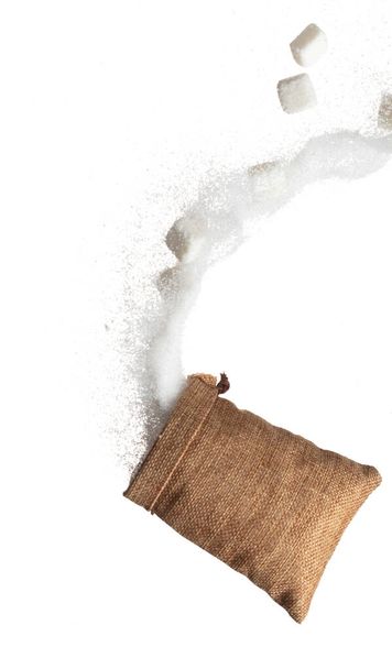 Sugar Cube in sack bag flying explosion, white crystal sugar fall abstract fly. Pure refined sugar cubes bag splash in air, food object design. white background isolated high speed freeze motion - Photo, Image