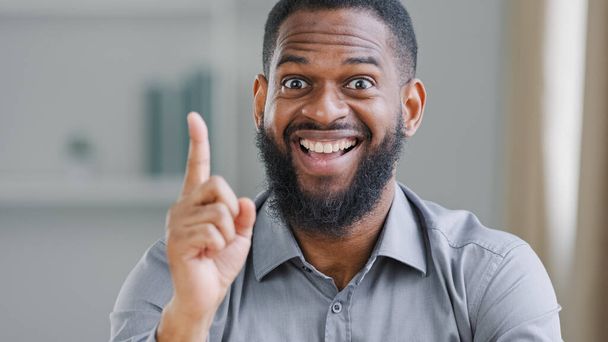 Happy exited bearded African American ethnic man entrepreneur businessman worker manager in office looking at camera rise forefinger index finger come up with good idea find answer perfect solution - Zdjęcie, obraz