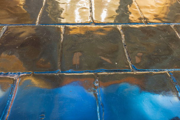 Close-up view of blue gold reflects on glossy floor tiles. Colorful background. - Foto, Imagem