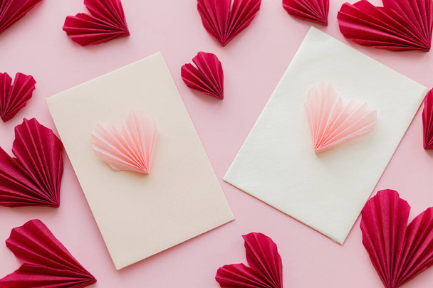 Hyvää ystävänpäivää! Tyylikäs kirjekuoret vaaleanpunainen ja punainen sydän tasainen makasi vaaleanpunainen paperi tausta. Moderni Ystävänpäivä sydämet leikkauksia. Rakkauskirje. Luova kokoonpano - Valokuva, kuva