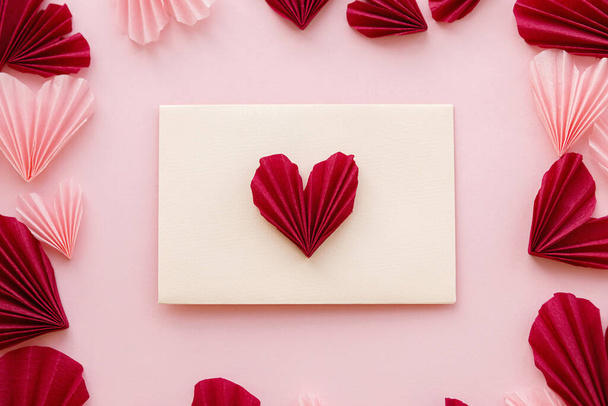 Ystävänpäivä tasainen lay. Tyylikäs kirjekuori vaaleanpunainen ja punainen sydän koostumus vaaleanpunainen paperi tausta. Luova moderni Ystävänpäivä sydämet leikkauksia. Hyvää ystävänpäivää! Rakkauskirje - Valokuva, kuva