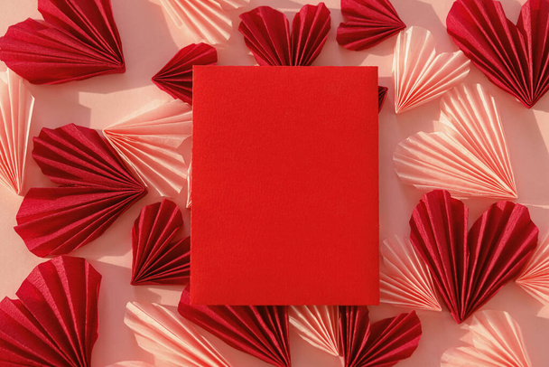 Стильная пустая красная карточка и розовые и красные сердца плоские лежали на розовом бумажном фоне. Современная валентинка с вырезанным сердцем. Любовное письмо. С Днем Святого Валентина! Творческая композиция - Фото, изображение