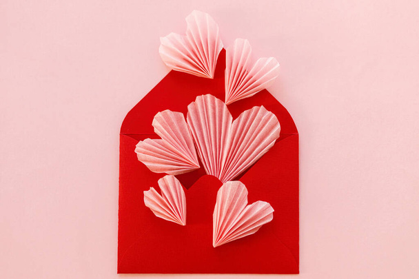 З днем Святого Валентина! Стильний червоний конверт з рожевими сердечками плоский лежав на фоні рожевого паперу. Сучасні валентинки серця. Любовний лист, простір для тексту. Творча композиція
 - Фото, зображення