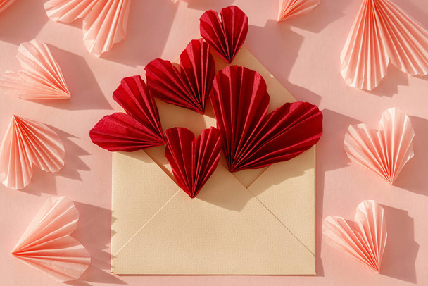 З днем Святого Валентина! Стильний конверт з червоними і рожевими сердечками плоский лежав на фоні рожевого паперу. Сучасна валентинка з серцевими скороченнями. Любовний лист. Творча композиція
 - Фото, зображення