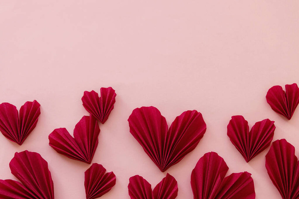 С Днем Святого Валентина! Стильные красные сердца плоские лежали на розовом бумажном фоне. Современные милые валентинки с вырезанным сердцем, место для текста. Креативное знамя любви - Фото, изображение
