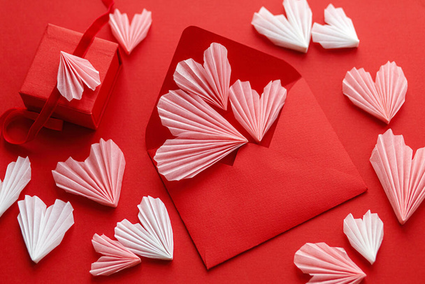 З днем Святого Валентина! Стильний червоний конверт з рожевими сердечками і подарунковою платою лежить на червоному паперовому тлі. Сучасна валентинка з серцевими скороченнями. Любовний лист. Творча композиція
 - Фото, зображення