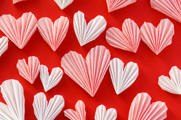 Ystävänpäivä tasainen lay. Tyylikäs vaaleanpunainen ja valkoinen sydän koostumus punaisella paperilla taustalla. Hyvää ystävänpäivää! Moderni söpö Ystävänpäivä sydän leikkauksia. Luova rakkauden banneri - Valokuva, kuva