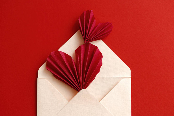 Ystävänpäivä tasainen lay. Tyylikäs kirjekuori punainen sydän koostumus punaisella paperilla taustalla. Luova moderni Ystävänpäivä sydämet leikkauksia. Hyvää ystävänpäivää! Rakkauskirje - Valokuva, kuva