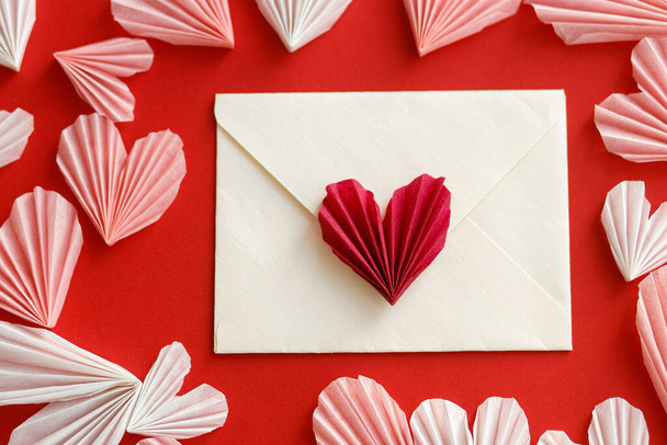 Hyvää ystävänpäivää! Tyylikäs kirjekuori vaaleanpunainen ja punainen sydän tasainen makasi punaisella paperilla taustalla. Creative moderni koostumus Ystävänpäivä sydämet leikkauksia. Rakkauskirje - Valokuva, kuva