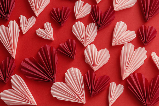 Hyvää ystävänpäivää! Tyylikäs vaaleanpunainen sydämet punaisella paperilla tausta tasainen lay. Moderni söpö Ystävänpäivä sydän leikkauksia koostumus. Luova rakkauden banneri - Valokuva, kuva