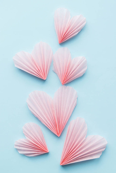 Ystävänpäivä tasainen lay. Tyylikäs vaaleanpunainen sydämet sinisellä paperilla taustalla. Hyvää ystävänpäivää! Moderni söpö Ystävänpäivä sydän leikkauksia koostumus. Luova rakkausjuliste - Valokuva, kuva