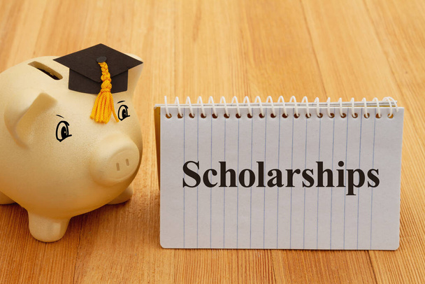 Scholarships message with gold piggy bank with a grad cap on wood desk for your money or saving for school - Foto, immagini
