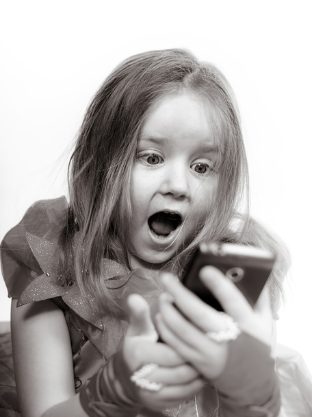 Cute little girl dressed in ball gown playing with smartphone  - Foto, afbeelding