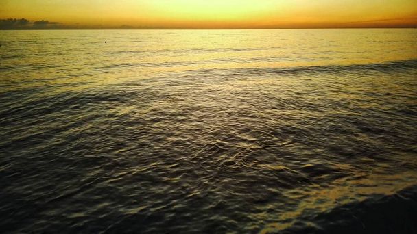 ビーチでの黄金の夕日-太陽の光の下で白い砂浜に向かって転がり泡立つ波の遅い動き. - 写真・画像