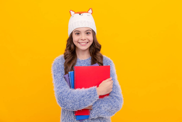 happy teen girl wear hat holding notebook on yellow background, homework. - Foto, Bild