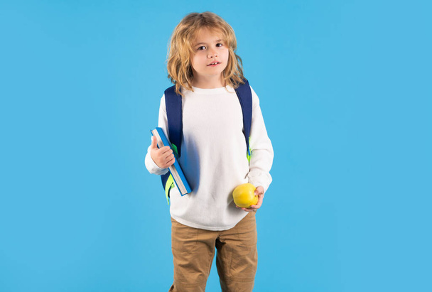 Малюк насолоджується школою. Шкільний хлопчик у шкільній формі з рюкзаком на синьому ізольованому фоні. Діти вивчають знання та концепцію освіти
 - Фото, зображення
