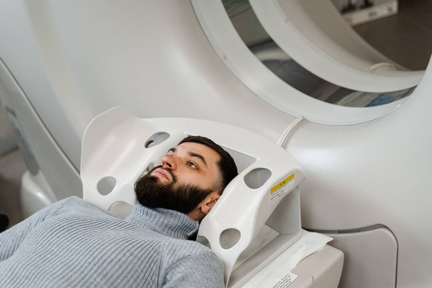 αξονική τομογραφία εγκεφάλου ανθρώπου στην ιατρική κλινική. Ο άνθρωπος κάνει αξονική τομογραφία ακτινογραφία εξέταση του όγκου στο κεφάλι του σε μια αξονική τομογραφία δωματίου - Φωτογραφία, εικόνα