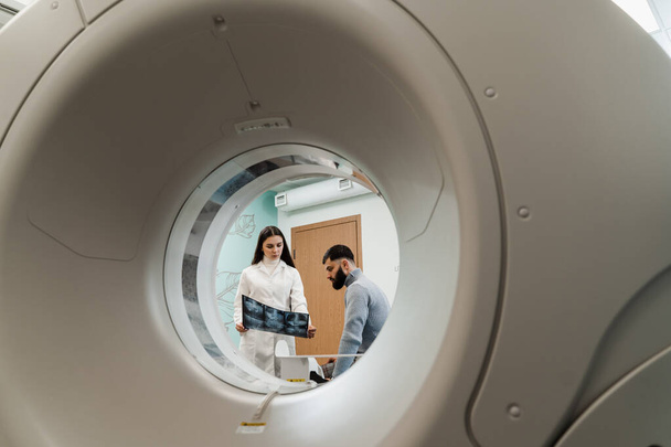 MRI医師は、男性患者の腹部のX線を示しています.診療所でのMRI検査後の相談 - 写真・画像