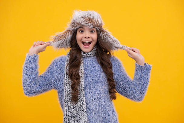 Beautiful winter kids portrait. Teenager girl posing with winter sweater and knit hat on yellow background. Excited teenager girl - Foto, immagini
