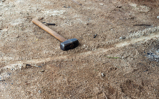 The handyman has left his sledge hammer on the dry parched ground. The tool is designed to deliver blunt force to an area or object. - Photo, image