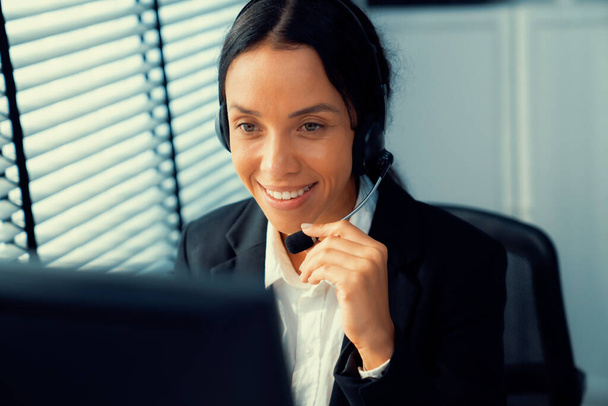 Competent female operator working on computer and talking with clients. Concept relevant to both call centers and customer service offices. - Foto, afbeelding