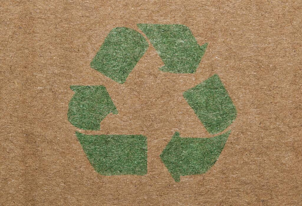 Green recycle symbol printed on a cardboard box, closeup isolated macro view. - Photo, Image