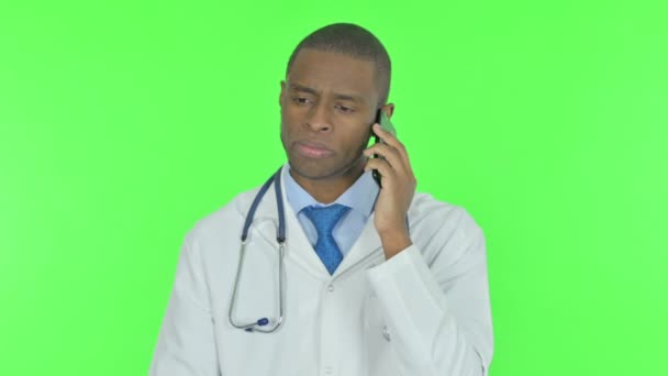 Young African Doctor Talking on Phone on Green Background - Felvétel, videó