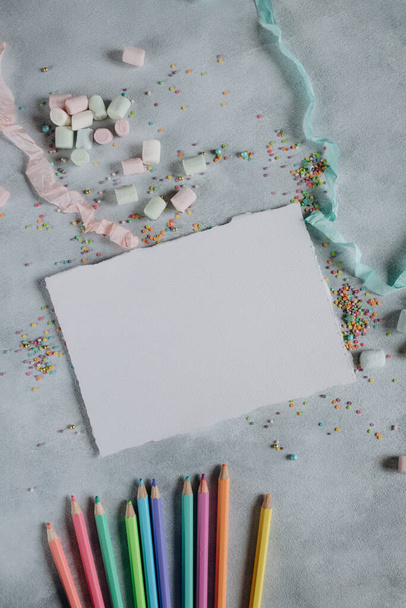 mockup of a sheet of white paper on a gray background with pencils and colored confetti, mockup of card or invitation for a holiday, paper with a texture - Zdjęcie, obraz