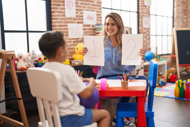 Δάσκαλος και νήπιο κάθεται στο τραπέζι έχοντας μαθηματικά μάθημα στο νηπιαγωγείο - Φωτογραφία, εικόνα