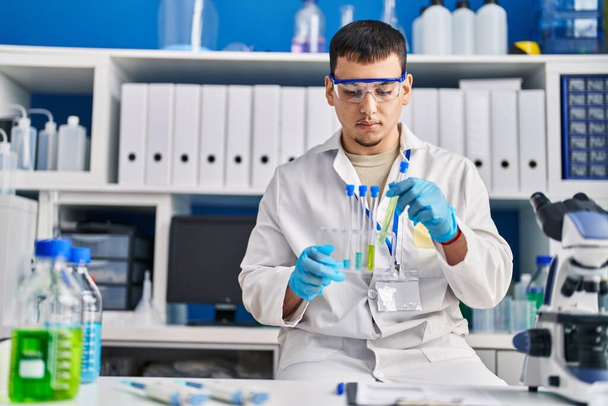 Νεαρός επιστήμονας που κρατά δοκιμαστικούς σωλήνες στο εργαστήριο - Φωτογραφία, εικόνα