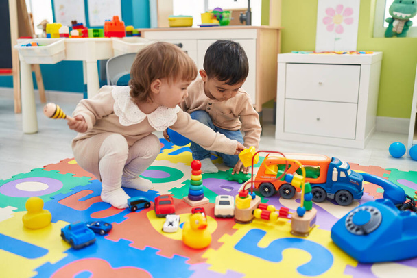 Two kids playing with cars toy sitting on floor at kindergarten - Photo, Image