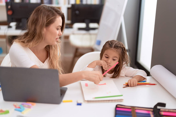 Professor e criança sentados na mesa desenhando em caderno na sala de aula - Foto, Imagem