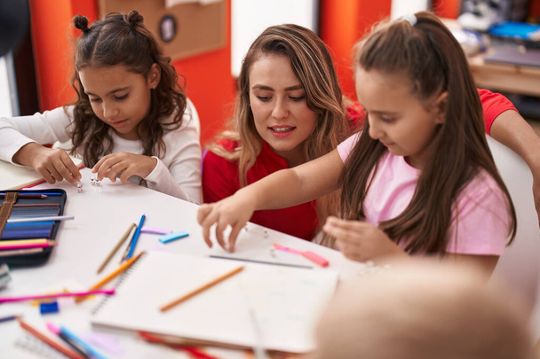 Група дітей студенти і вчитель сидить на столі малюючи на папері в класі
 - Фото, зображення