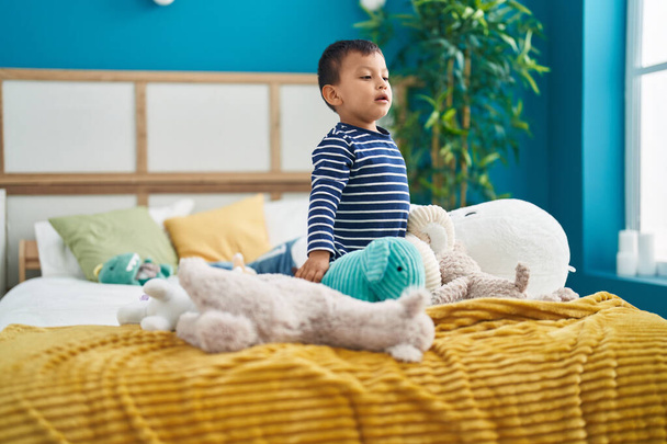 Αξιολάτρευτο ισπανόφωνο νήπιο που παίζει με κούκλες στο κρεβάτι στο υπνοδωμάτιο - Φωτογραφία, εικόνα