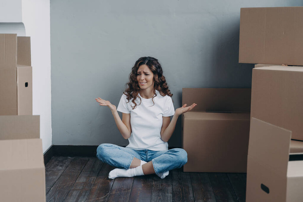 Nervous european woman has to pack the boxes. Girl is upset with moving. Annoyed young lady in jeans and white t-shirt is going to relocate. Homeowner getting stress from moving concept. - Fotó, kép