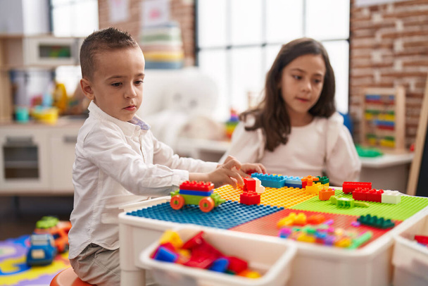 Hermano y hermana jugando con bloques de construcción sentados en la mesa en el jardín de infantes - Foto, imagen