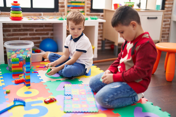 Dos niños jugando con bloques de construcción y matemáticas juego de puzzle sentado en el suelo en el jardín de infantes - Foto, Imagen