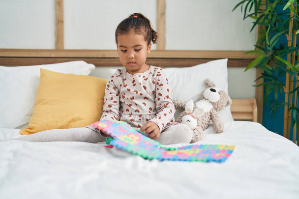 Adorabile ragazza ispanica giocare matematica gioco seduto sul letto in camera da letto - Foto, immagini