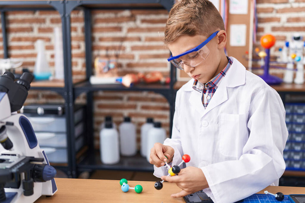 Adorable caucasian boy student holding molecules at classroom - Photo, Image