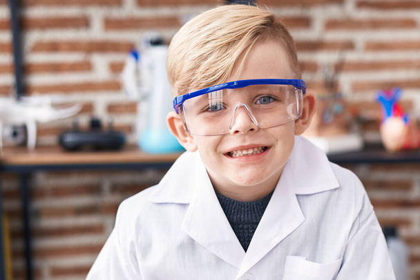 Очаровательный юный ученый улыбается уверенно стоя в классе - Фото, изображение