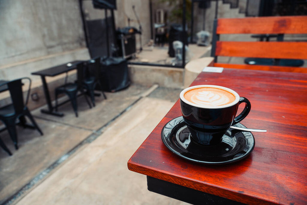 cappuccino on the corner of a brown wooden table with copy space. great for coffee drink ads - Foto, afbeelding