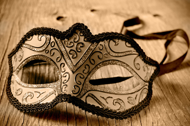 máscara de carnaval en una superficie de madera en tonificación sepia
 - Foto, imagen